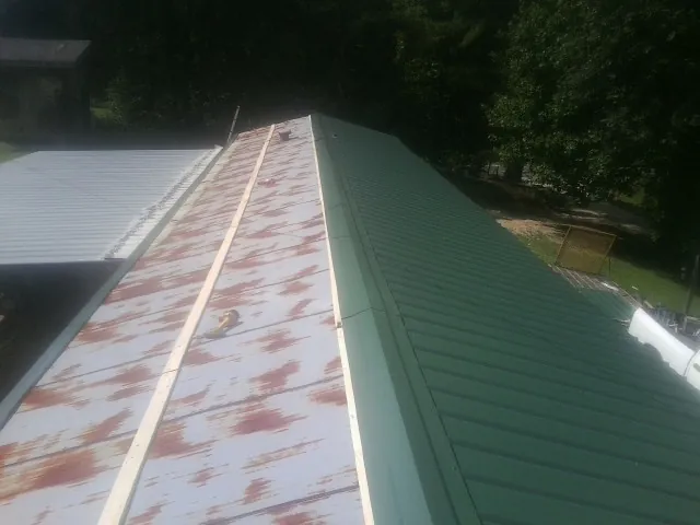 Old rusted panels beside newly installed green metal roofing — Wind Damage Roof Repair by Roofing Brothers in Barnett