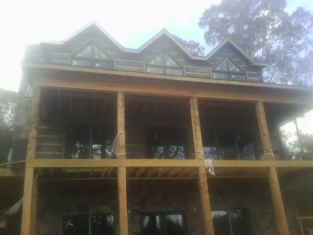 Dormers and porch framing on a large log home under construction — Roof Coating work by our crew in Barnett