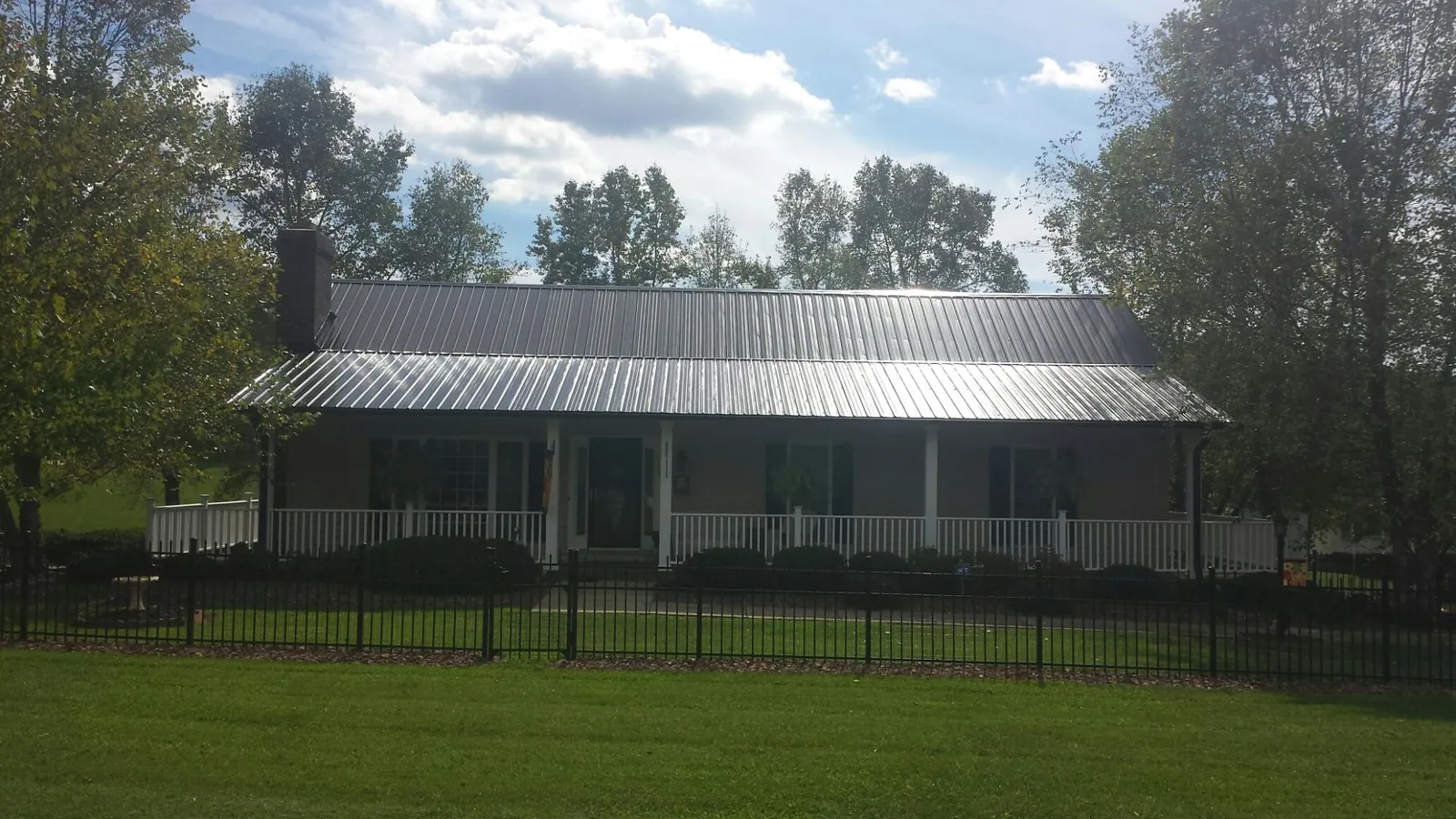 Gray metal roof on a brick ranch with a full width front porch — Gutter Guard Installation work by our crew in Barnett