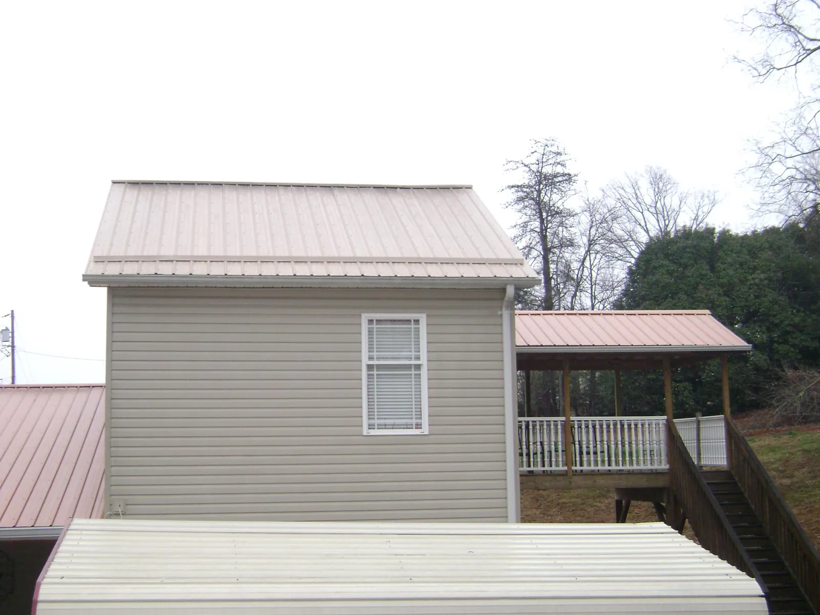 Tan metal roofs on a two story addition and attached porch, from a Roof Replacement job in Barnett