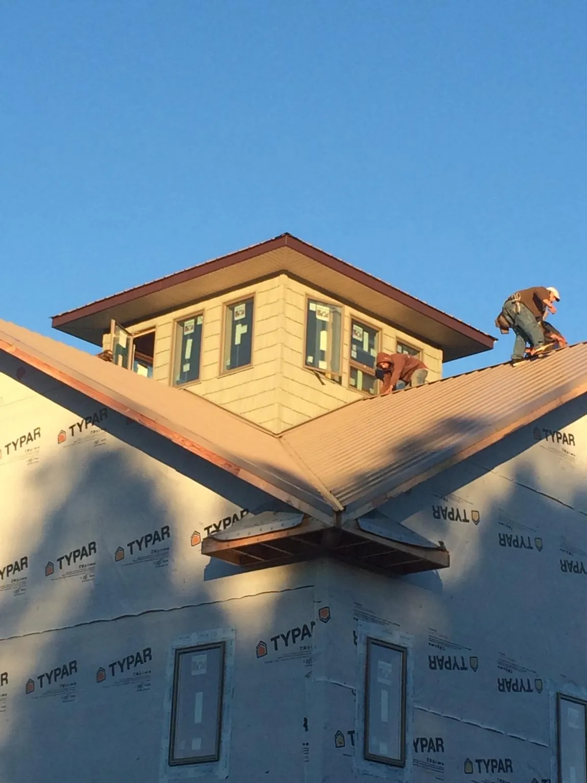 Roofers working around a rooftop cupola on a new metal roof at sunset — Roof Waterproofing in Barnett by Roofing Brothers